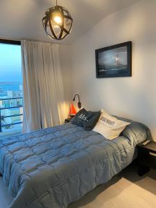 ein Schlafzimmer mit großem Bett und Fenster in der Unterkunft Departamento frente al mar. Terraza y cochera privadas. Parrilla. in Puerto Madryn