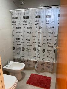 ein Badezimmer mit Toilette und Duschvorhang in der Unterkunft Departamento frente al mar. Terraza y cochera privadas. Parrilla. in Puerto Madryn