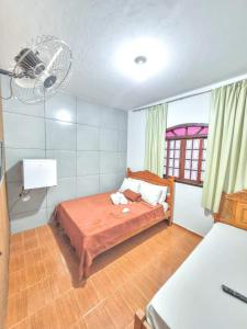 um quarto com uma cama, uma ventoinha e uma janela em Pousada Iasbeck em Santa Rita de Jacutinga