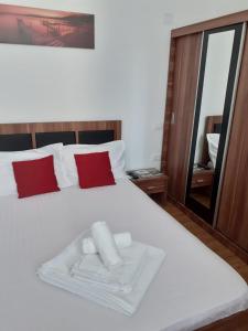 Schlafzimmer mit einem weißen Bett mit roten Kissen und einem Spiegel in der Unterkunft Apartament Noblesse, complex Apolonia-Eforie Nord in Eforie Nord
