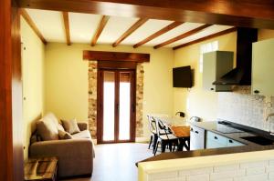 a kitchen and living room with a couch and a table at Apartamentos La Rosa y El Pastor in Guijo de Santa Bárbara