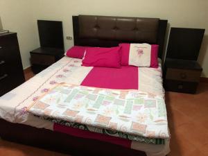 a large bed with pink pillows and a blanket at بورتو السخنة الاهرامات in Cairo