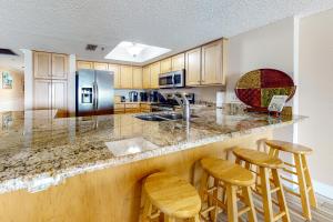 a kitchen with wooden cabinets and a counter with stools at Ram Sea I 301 in St. Pete Beach