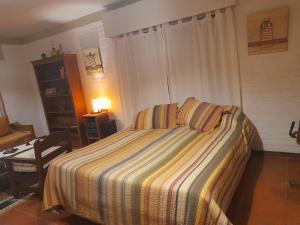 1 dormitorio con 1 cama con manta a rayas en Habitación Gabriela Mistral, en Colonia del Sacramento