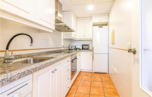 une cuisine avec des armoires blanches, un évier et un réfrigérateur dans l'établissement Cozy Home In Finestrat With Wifi, à Finestrat