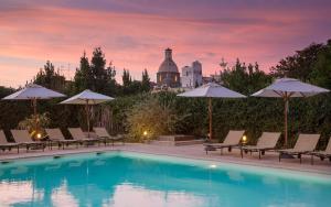 a pool with chairs and umbrellas and a building at Boutique Hotel Casa Mariantonia in Anacapri