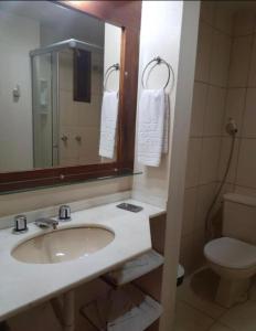 a bathroom with a sink and a toilet and a mirror at Pousada do Serrano - Rua Torta in Gramado