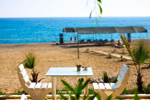 una mesa y sillas en una playa con el océano en Naz Beach Bungalow Hotel in Antalya, en Kızılot