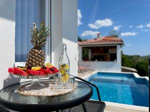 a pineapple on a glass table next to a pool at La Mer Apartments Kotor in Kotor