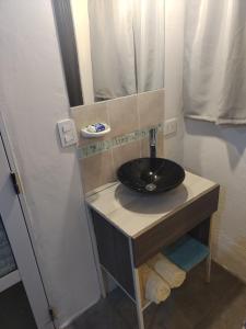 uma casa de banho com um lavatório preto e um espelho em La Gloria em Merlo