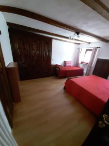 1 dormitorio con 2 camas rojas y ventana en Casa Elena en Nus