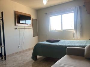 a bedroom with a bed and a window and a tv at Joneson aluga QUITINETE próximo a Praia do Forte até 4 pessoas in Cabo Frio