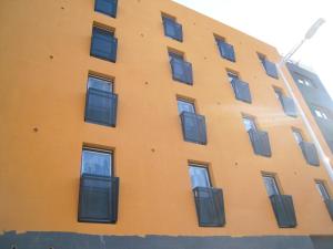 un bâtiment jaune avec des fenêtres latérales dans l'établissement Bel appartement neuf climatisé & parking, à Perpignan