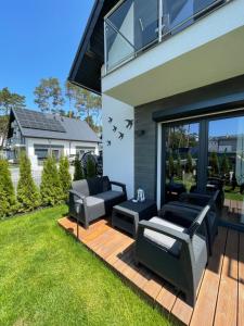 - un patio avec deux canapés et des chaises sur une terrasse dans l'établissement Blue Wave Garden, à Dziwnówek