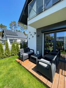 a patio with two couches and chairs on a deck at Blue Wave Garden in Dziwnówek