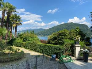un jardín con vistas al lago y a las montañas en Castello mit Park, en Ponte Tresa