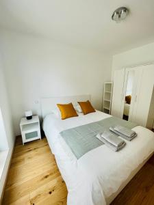 ein weißes Schlafzimmer mit einem großen weißen Bett und orangefarbenen Kissen in der Unterkunft Brand New 2 bedrooms with Parking and Terrace - 142-96 in Luxemburg (Stadt)