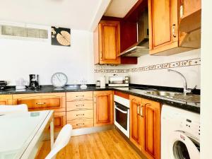 cocina con armarios de madera, fregadero y lavavajillas en Sea View Escape in La Garrofa, en La Garrofa