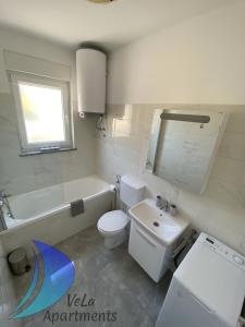 biała łazienka z umywalką i toaletą w obiekcie VeLa Apartments w mieście Ičići +29 zdjęć