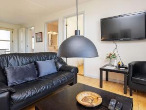a black leather couch in a living room with a tv at Apartment Hals IV in Hals