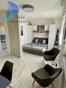 sypialnia z łóżkiem i krzesłami w pokoju w obiekcie VeLa Apartments w mieście Ičići