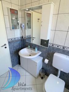 łazienka z umywalką, toaletą i lustrem w obiekcie VeLa Apartments w mieście Ičići