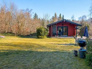 una cabina roja en un campo con patio en 4 person holiday home in Nibe en Nibe