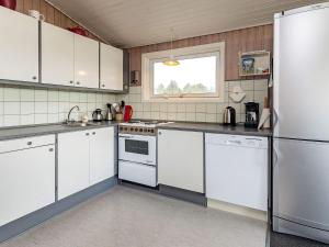 バイアス・スタンにある6 person holiday home in Vejers Strandのキッチン(白いキャビネット、冷蔵庫付)