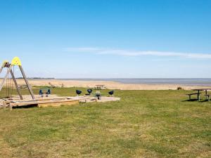 a playground in a field next to the beach at 8 person holiday home in R m in Bolilmark