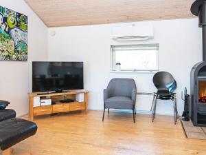 a living room with a flat screen tv and two chairs at Four-Bedroom Holiday home in Hemmet 7 in Falen