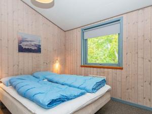 Bett mit blauer Bettwäsche in einem Zimmer mit Fenster in der Unterkunft 8 person holiday home in B rkop in Børkop