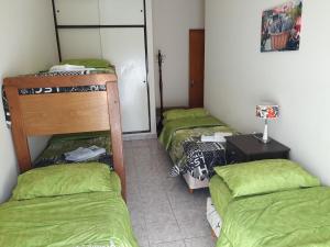 3 stapelbedden in een kamer met groene lakens bij DUPLEX DEVoTO 5238 in Buenos Aires