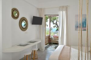 - une chambre blanche avec un lit, un bureau et une fenêtre dans l'établissement Niriis Studio 7 Batsi Andros, à Batsi
