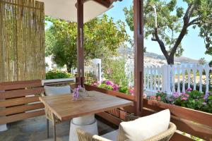 - une terrasse couverte avec une table en bois, des chaises et des fleurs dans l'établissement Niriis Studio 7 Batsi Andros, à Batsi