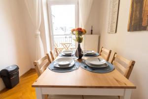 stół jadalny z talerzami i wazon kwiatów w obiekcie Deluxe apartment near hauptbahnhof w Wiedniu