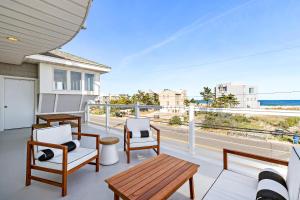 Un balcón con sillas y mesas y vistas al océano. en The Hideaway Hotel en Long Beach