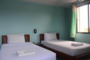 two beds in a room with blue walls and a window at Grand Mansion Hotel in Krabi town