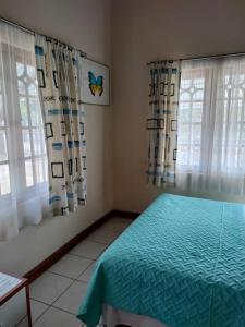 a bedroom with a bed and two windows with curtains at Zuri Enterprise in Negril