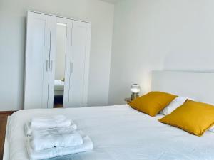 ein weißes Bett mit gelben Kissen und Handtüchern darauf in der Unterkunft Brand New 2 bedrooms with Parking and Terrace - 142-96 in Luxemburg (Stadt)