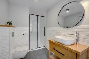 ein weißes Badezimmer mit einem Waschbecken und einem Spiegel in der Unterkunft Chata i Mostek in Krynica-Zdrój