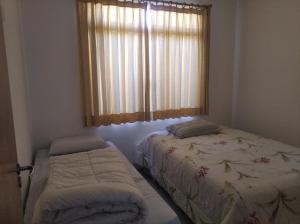 a bedroom with two beds and a window at Cs9 Casa de 3 quartos a 15 min de Curitiba in Campina Grande do Sul