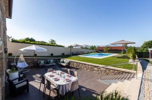 un patio con mesa, sillas y piscina en O CERVO CHARM HOUSE, en Vila Nova de Cerveira