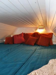 a bed with red pillows on it in a tent at Sjönära liten stuga med sovloft, toilet in other small house, no shower in Åkersberga