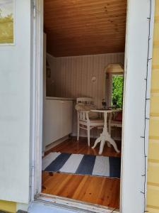 una puerta abierta de una habitación con una mesa y una mesa en Sjönära liten stuga med sovloft, toilet in other small house, no shower, en Åkersberga