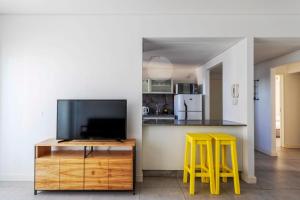 eine Küche mit einem TV und zwei gelben Stühlen in der Unterkunft DONA Chic! in Puerto Madryn