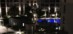 a night view of a pool with palm trees and buildings at Marassi Marina in El Alamein