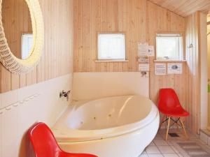 a bathroom with a tub and a red chair at 8 person holiday home in V ggerl se in Marielyst