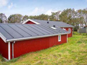 a red barn with a metal roof on a hill at 6 person holiday home in Thisted-By Traum in Thisted