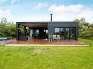 YderbyにあるHoliday home Sjællands Odde XIIのデッキと芝生のあるモダンな黒い家