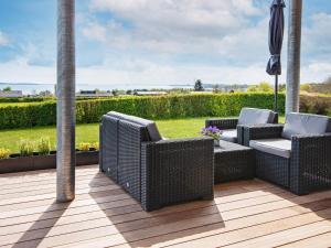 a patio with wicker chairs and an umbrella at 6 person holiday home in R nde in Rønde